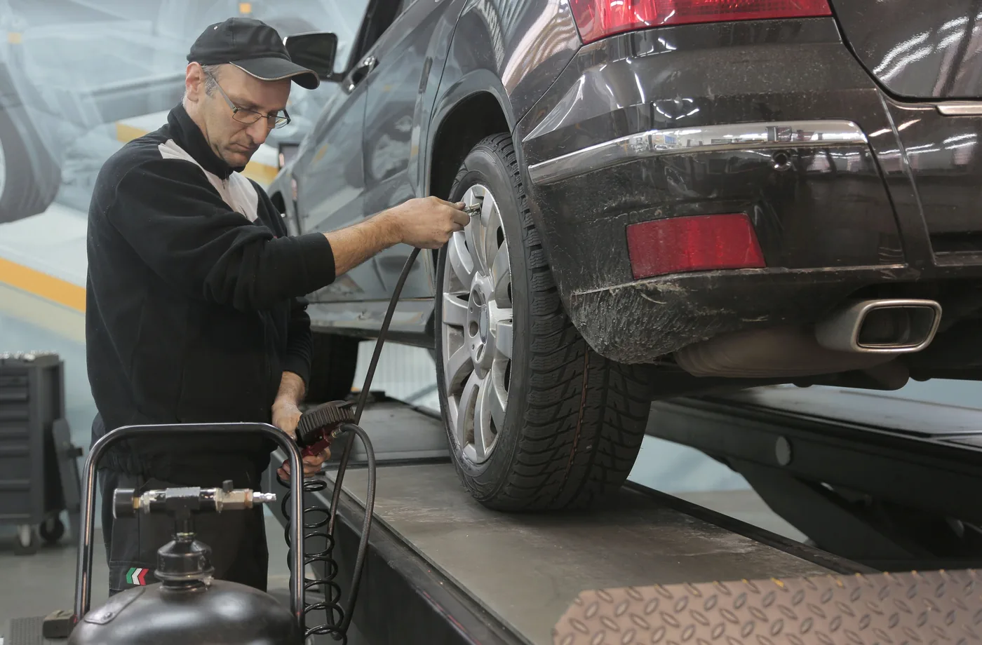 Mechaniker prüft einen Reifen an einem angehobenen Fahrzeug