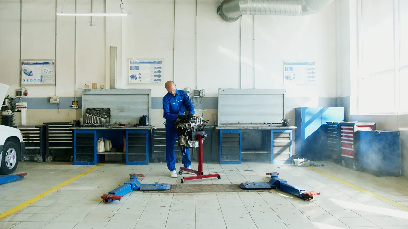 Helle Werkstatt mit Mechaniker an einem Motoraggregat